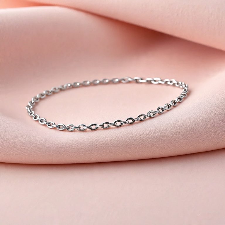 Elegant silver chain bracelet displayed on soft pink fabric background.